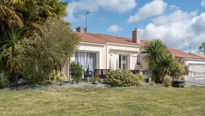 A two-story house with a tiled roof, surrounded by a grassy lawn and various plants. - La Lilla - Piscine - Wifi (Chauve)