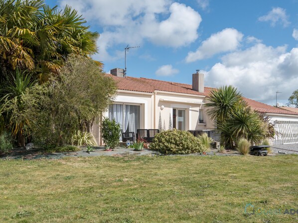 A two-story house with a tiled roof, surrounded by a grassy lawn and various plants. - La Lilla - Piscine - Wifi (Chauve)