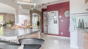 A modern kitchen with a central island, stainless steel appliances, and a red accent wall. - La Lilla - Piscine - Wifi (Chauve)