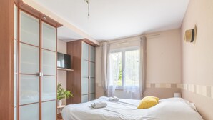 A bedroom with a bed, a wardrobe, a television, and a window with curtains. - La Lilla - Piscine - Wifi (Chauve)
