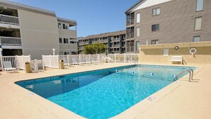 Une piscine rectangulaire à l’eau d’un bleu limpide, entourée d’une terrasse sablonneuse.