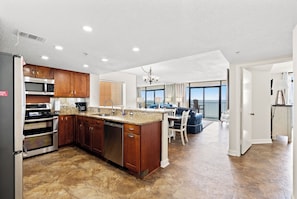 Kitchen features a central island with a sink, stainless steel appliances, and wooden cabinets.
