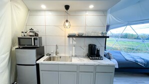 Cocina compacta equipada con microondas, refrigerador, lavaplatos y cafetera.