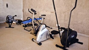 Een kamer met een hometrainer, een roeimachine en een loopband.