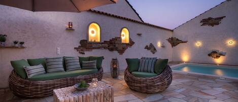 A patio area with two wicker sofas, a small wooden table, and a pool.