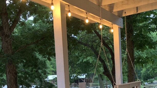An outdoor seating area with a swing, string lights, and a pergola structure. - Private COVE! Bring or rent boat for delivery. Boat Ramp/Dock/Kayak/SUPs/Fishing (Camdenton)