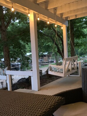 An outdoor seating area with a swing, string lights, and a pergola structure. - Private COVE! Bring or rent boat for delivery. Boat Ramp/Dock/Kayak/SUPs/Fishing (Camdenton)