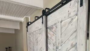 A room with a sliding barn-style door, a small white table with a lamp, and a dark blue sofa. - Private COVE! Bring or rent boat for delivery. Boat Ramp/Dock/Kayak/SUPs/Fishing (Camdenton)