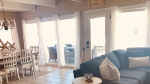 A spacious living room with a large grey sofa, a small round table, and a dining area with white chairs and starfish decorations. - Private COVE! Bring or rent boat for delivery. Boat Ramp/Dock/Kayak/SUPs/Fishing (Camdenton)