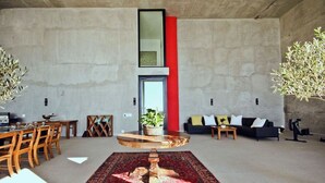 Uma sala de estar ampla com teto alto, uma mesa de centro redonda, um sofá e um espaço de jantar com cadeiras e uma mesa.