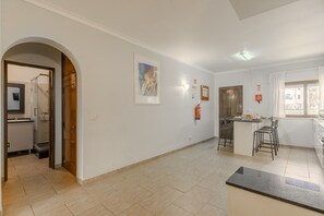 Eine geräumige Küche mit einer zentralen Kochinsel, einem Essbereich mit Stühlen und einem großen Fenster mit Vorhängen.