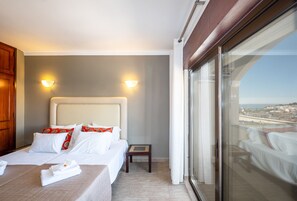 Ein Hotelzimmer mit Bett, Nachttisch und Blick durch ein großes Fenster.