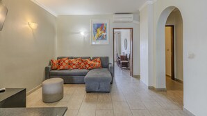Un soggiorno con un divano grigio, un poggiapiedi e un quadro appeso al muro.