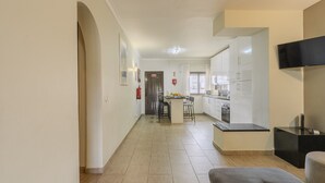 Una cucina moderna con mobili bianchi, un piano di lavoro nero e una piccola isola con sgabelli da bar.
