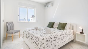 Una camera da letto con un letto, una sedia, un comodino e una finestra con vista.