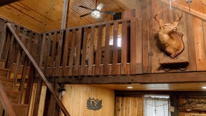 Ein Holzinterieur mit Deckenventilator, einem aufgehängten Hirschgeweih und einer Holztreppe.