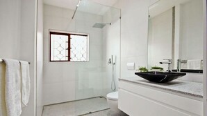 A modern bathroom with a glass-enclosed shower, a white toilet, and a large mirror above a black sink. - CAPTAIN'S COTTAGE (Cape Town)