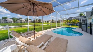 A poolside area with lounge chairs and a canopy umbrella. - Sunset Villa, Minutes from Disney. Exclusive 4 Bed, 2.5 Bath Pool Home (Kissimmee)