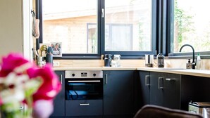 Una cocina moderna con un ventanal grande, armarios oscuros y techo de madera.