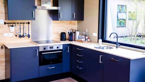 A modern kitchen with dark cabinets, stainless steel appliances, and a window providing a view of the outside. - Nature lodge Skries, Akkrum - sleeps 8, 3 bedrooms (Akkrum)