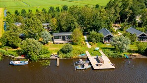 Een landgoed aan het meer met aangemeerde boten, een houten steiger en een huis omringd door weelderige begroeiing.
