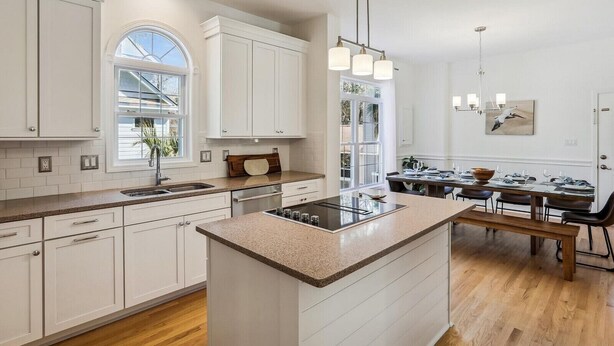 Une cuisine moderne avec des meubles blancs, un îlot central et un coin repas équipé d’une banquette.