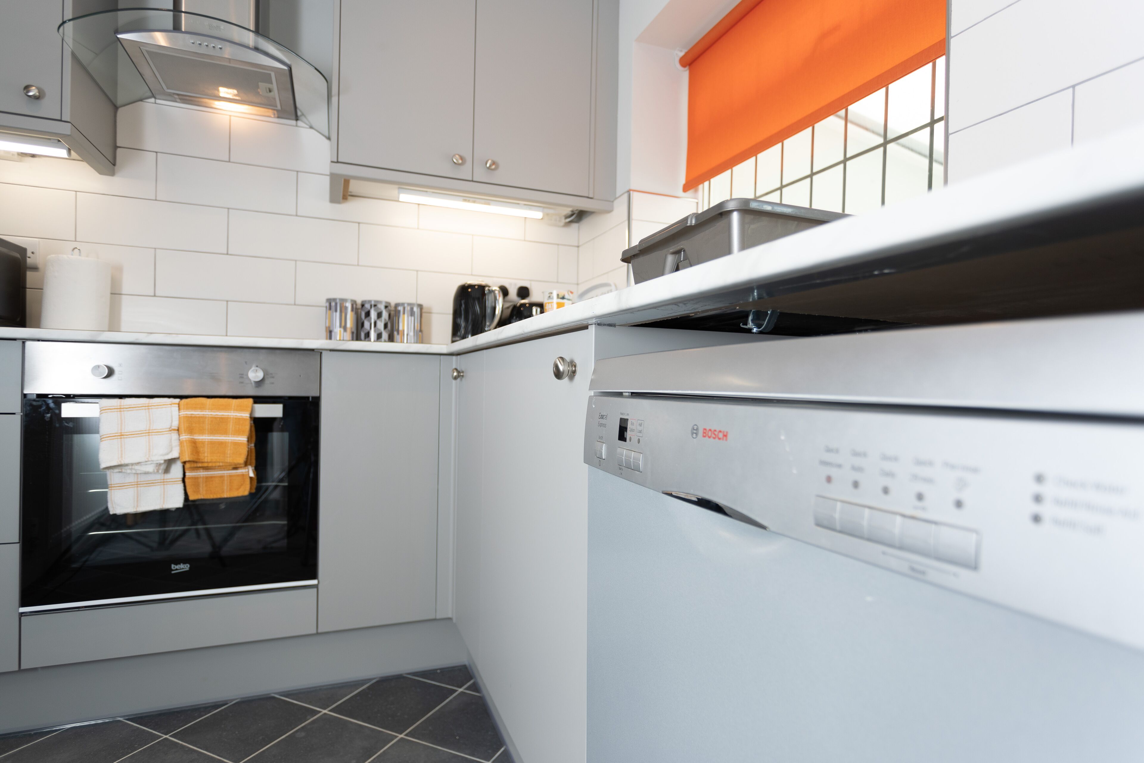 Een moderne keuken met witte kasten, een Bosch vaatwasser en een oven.