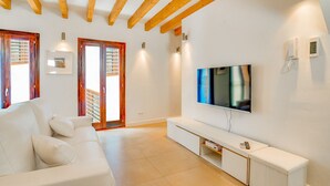 A modern living room with a white sofa, wooden beams, a flat-screen TV, and a sliding glass door leading to a balcony. - DUPLEX PALMA APARTMENT ETV/5551 (Palma de Mallorca)