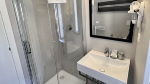 A modern bathroom with a glass-enclosed shower, a white sink, and a mirror above it. - Family Room inside the Guesthouse on the Arch (Monterosso al Mare)