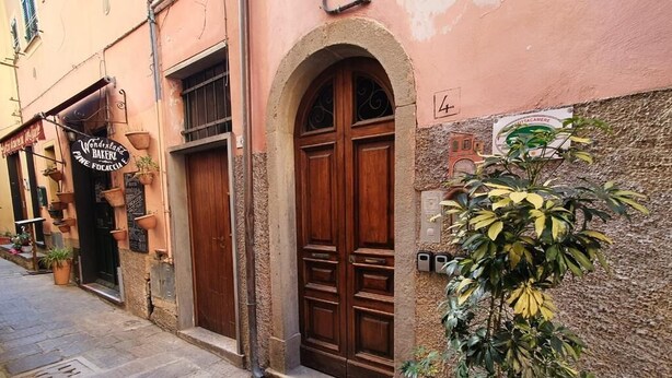 A building with a large wooden double door and a sign for 'Venezia Bakery'. - Camera Singola All'interno di un Affittacamere in Pieno Centro Storico (Monterosso al Mare)