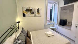 A bedroom with a bed, a window, a wall-mounted TV, and a small balcony. - Camera Singola All'interno di un Affittacamere in Pieno Centro Storico (Monterosso al Mare)