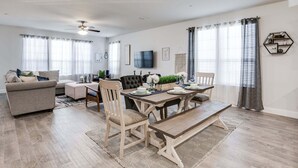 Un salon moderne avec un coin repas, comprenant un canapé, des fauteuils, une table à manger et un ventilateur de plafond.