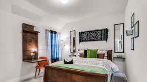 Une chambre à coucher avec un lit en bois, un bureau, une chaise et un miroir.