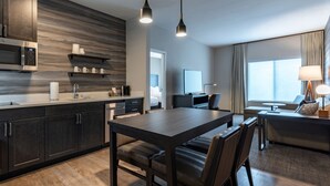 Een moderne hotelkamer met een donker houten eettafel, een flatscreen televisie, een bank en een groot raam met uitzicht.