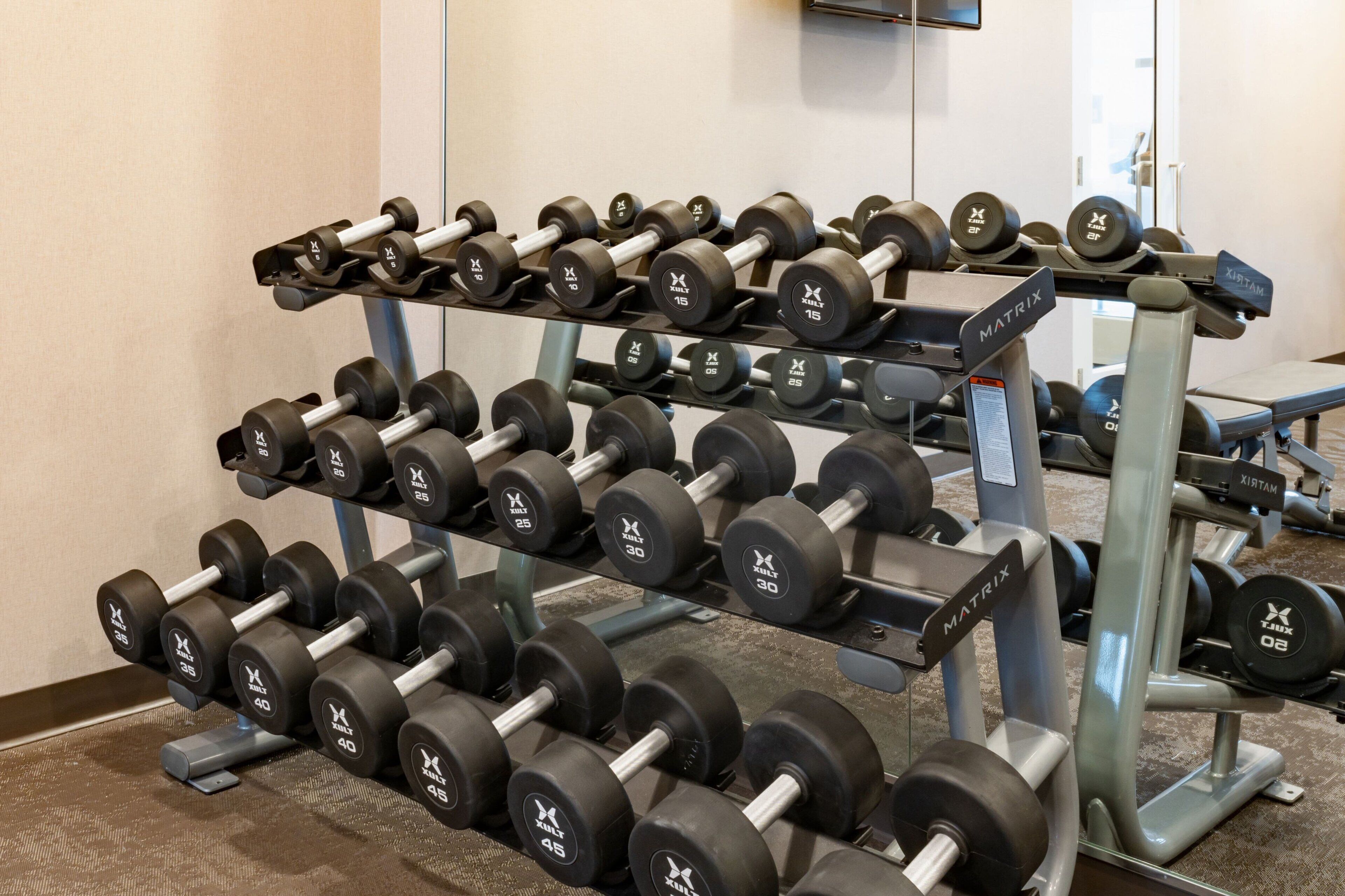 A weightlifting area with multiple sets of dumbbells arranged on racks.
