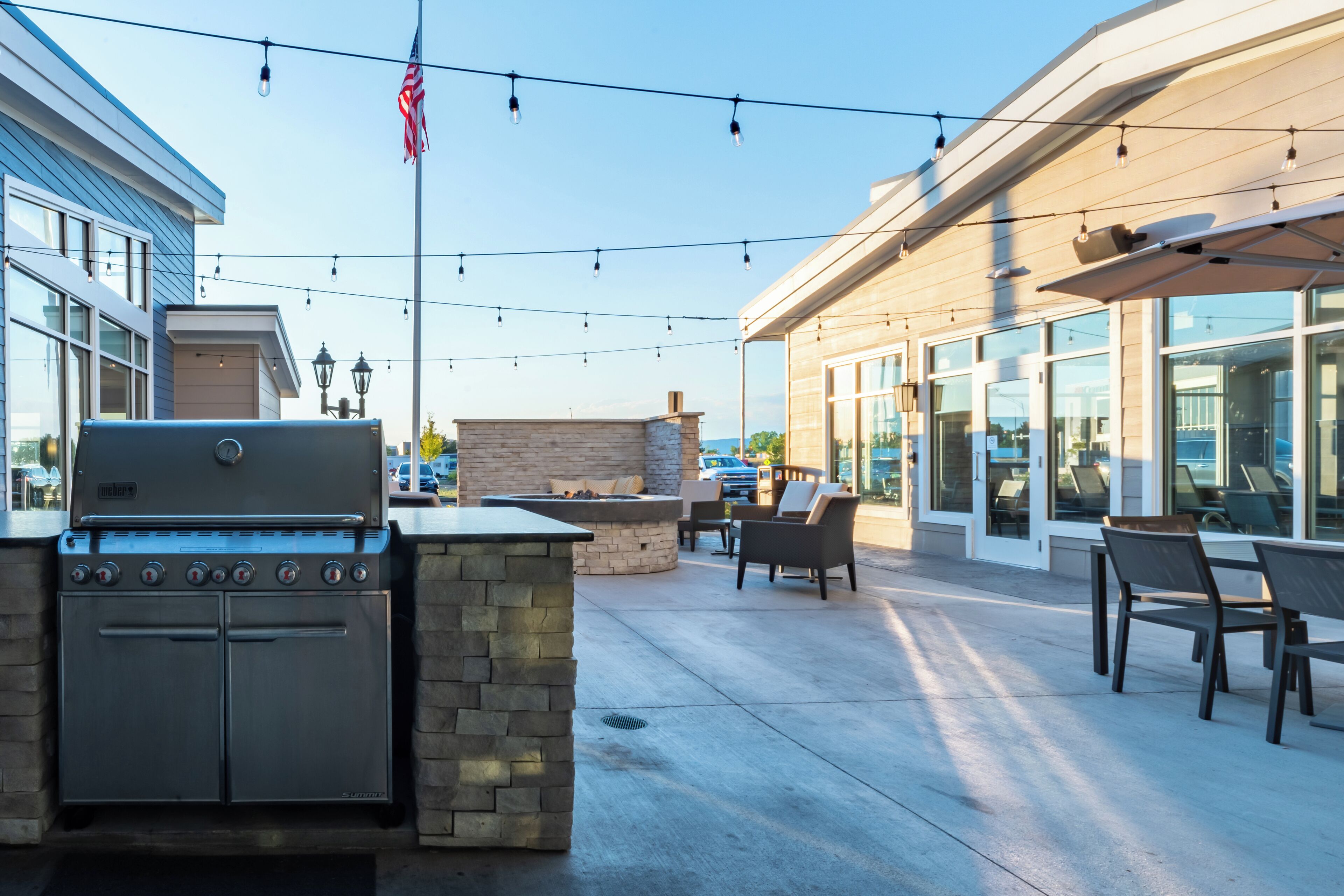 An outdoor patio with a built-in grill, seating area, and string lights.