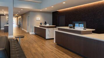 A modern hotel reception area with a marble counter, a black leather sofa, and a brick-patterned wall.
