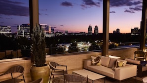 A rooftop lounge with a city view, featuring a sofa, chairs, and a large vase. - AC Hotel Atlanta Perimeter (Atlanta)