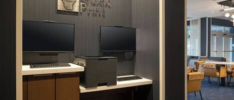 Un espace de bureau moderne équipé de deux écrans, d’une imprimante et d’un clavier, le tout posé sur un bureau.