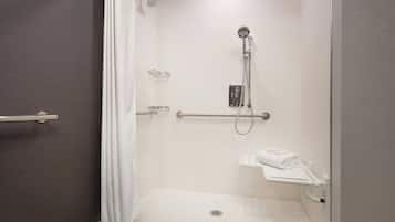 A modern bathroom with a shower, grab bar, and towel rack.