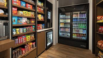 A snack and beverage section with shelves stocked with various snacks and a refrigerator with multiple beverage options.