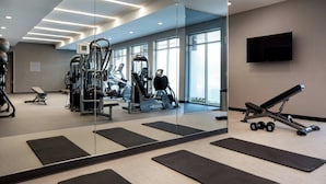 A modern gym with exercise equipment, black mats, and a TV on the wall. - Courtyard by Marriott Fresno Clovis (Clovis)