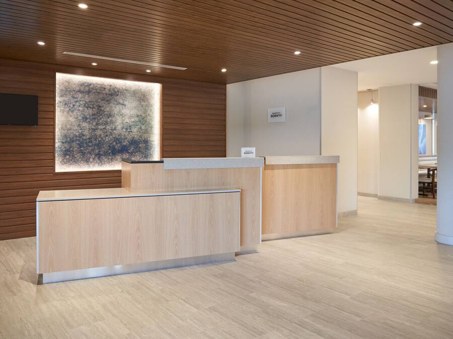 A reception area with wooden panel walls, a large abstract artwork, and a modern reception desk.