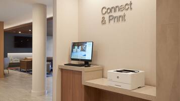A reception desk with a computer monitor, a printer, and a sign that reads "Connect & Print".