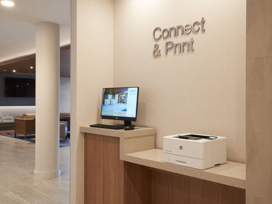 A reception desk with a computer monitor, a printer, and a sign that reads "Connect & Print".