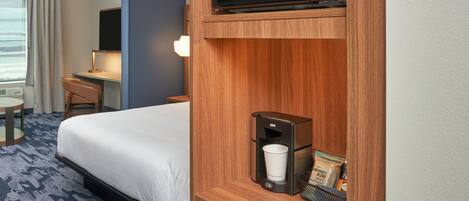 Une chambre d’hôtel équipée d’un lit, d’un bureau, d’un four à micro-ondes, d’une machine à café et offrant une vue sur la mer.