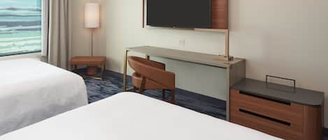 Quarto de hotel com duas camas, uma escrivaninha, uma cadeira, televisão e janela com cortinas.