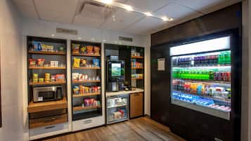 A self-service snack and drink station with microwaves, refrigerators, and shelves stocked with various food items and beverages.