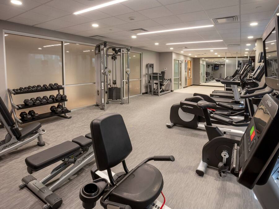 A gym with various exercise equipment including treadmills, weight machines, and dumbbells.