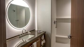 A modern bathroom with a round mirror, a sink, and a shower.